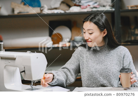 Professional young female tailor working in workshop 80970276