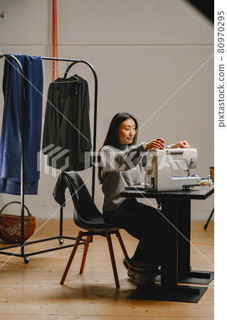 Professional young female tailor working in workshop 80970295