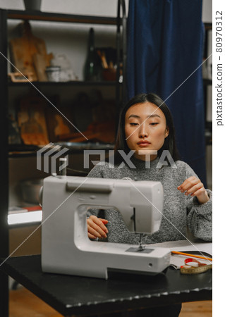 Professional young female tailor working in workshop Professional young female tailor working in workshop 80970312