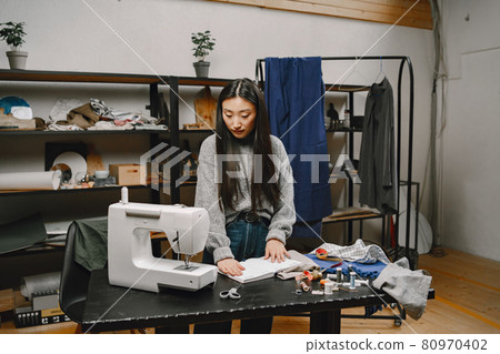 Professional young female tailor working in workshop Professional young female tailor working in workshop 80970402