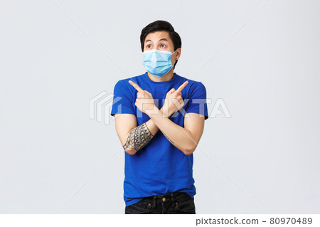 Different emotions, social distancing, quarantine on coronavirus and lifestyle concept. Indecisive and confused asian man in medical mask, pointing left and right, two ways, cant decide few choices 80970489