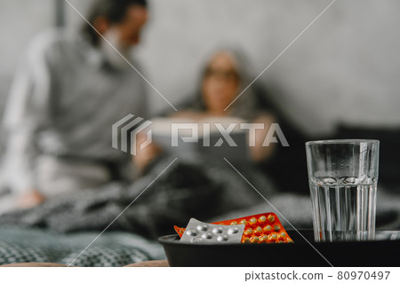 Pills and glass and senior couple on background Pills and glass and senior couple on background 80970497