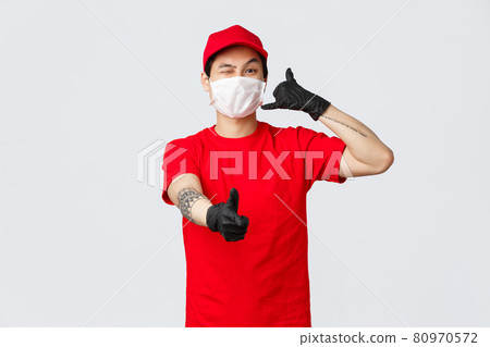 Call out customer support anytime. Cheerful asian delivery guy in medical mask and protective gloves, wink and show thumb-up, phone sign, provide safe courier service. carrier and shopping concept Call out customer support anytime. Cheerful asian delivery guy in medical mask and protective gloves, wink and show thumb-up, phone sign, provide safe courier service. carrier and shopping concept 80970572
