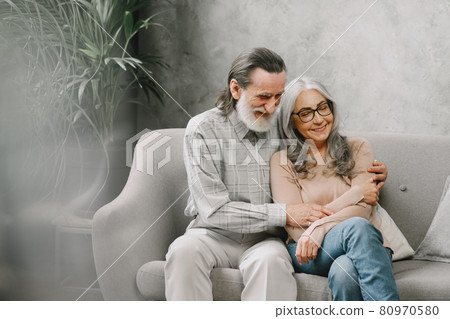 Senior couple in casual clothes sitting on couch in living room 80970580