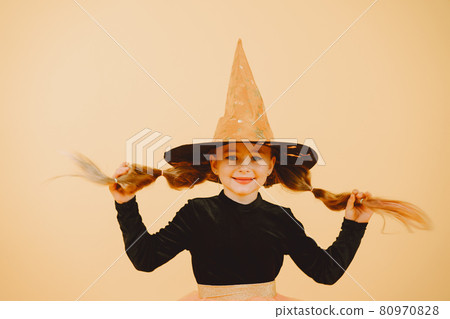 Beautiful girl witch on a orange background Beautiful girl witch on a orange background 80970828