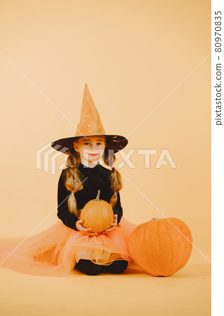 Beautiful girl witch on a orange background Beautiful girl witch on a orange background 80970835