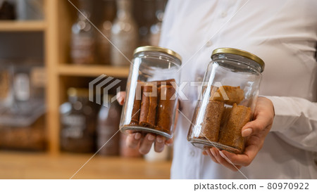 A woman holds a jar with Sweet pureed fruit pastila. Natural weight sweets in an eco store A woman holds a jar with Sweet pureed fruit pastila. Natural weight sweets in an eco store 80970922