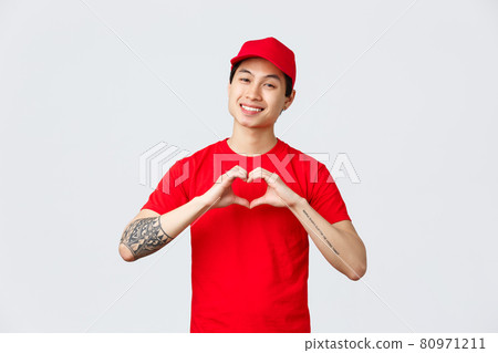 Express delivery, shipping and logistics concept. Friendly handsome asian courier in red cap and t-shirt, company uniform, show heart gesture and smiling delighted, care for customers and clients Express delivery, shipping and logistics concept. Friendly handsome asian courier in red cap and t-shirt, company uniform, show heart gesture and smiling delighted, care for customers and clients 80971211