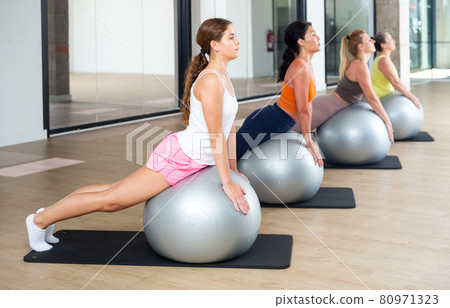 Women exercising with ball during group pilates class 80971323