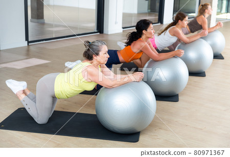 Women exercising in a gym. Sports women is training cross fitness with balls Women exercising in a gym. Sports women is training cross fitness with balls 80971367