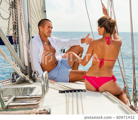 Smiling young couple talking while sitting on deck of their sail 80971432