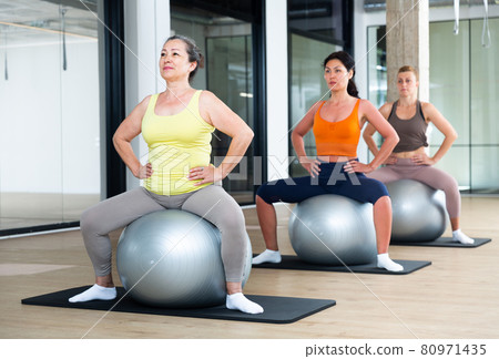 Women exercising with ball during group pilates class Women exercising with ball during group pilates class 80971435