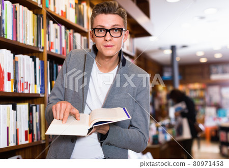 Surprised male student standing in library, pointing at somethin Surprised male student standing in library, pointing at somethin 80971458