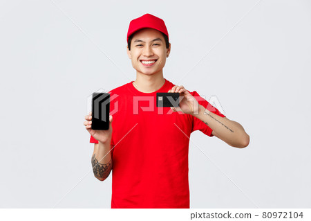 Delivery application, online shopping and shipping concept. Friendly smiling asian courier in red uniform cap and t-shirt recommend app, show smartphone and credit card Delivery application, online shopping and shipping concept. Friendly smiling asian courier in red uniform cap and t-shirt recommend app, show smartphone and credit card 80972104