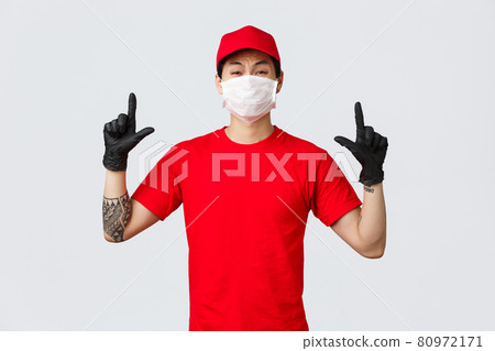 Reluctant or scared, insecure asian guy whining, grimacing as pointing fingers up, wear delivery uniform, red cap and t-shirt, company protect personnel health with protective masks and gloves 80972171