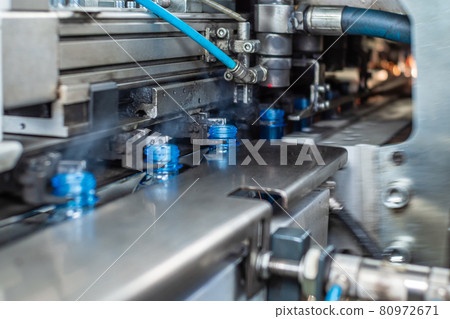 The newly blown plastic bottles come out of the blowing machine. Food production. 80972671