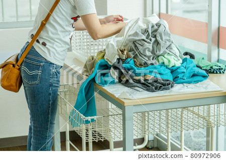 Housewife folding laundry in a laundromat 80972906