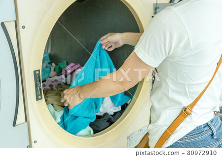 Housewife putting laundry in a coin laundry Housewife putting laundry in a coin laundry 80972910