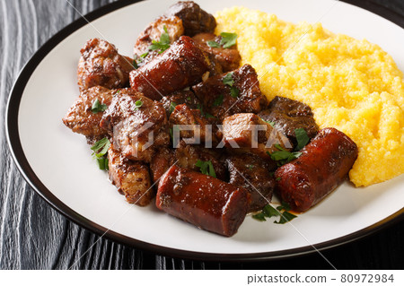 Romanian festive dish pomana porcului consisting of pieces of fried pork, sausages and offal served with corn porridge close-up on a plate. Horizontal Romanian festive dish pomana porcului consisting of pieces of fried pork, sausages and offal served with corn porridge close-up on a plate. Horizontal 80972984