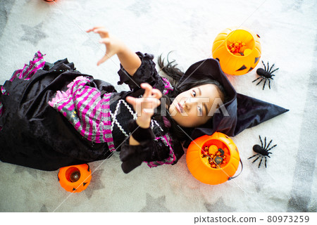 Top view portrait of little girl with witch dress plays in the room decorated in Halloween festival Top view portrait of little girl with witch dress plays in the room decorated in Halloween festival 80973259
