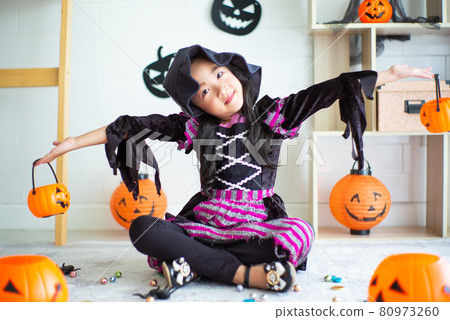 Portrait of little girl with witch dress plays in the room decorated in Halloween festival 80973260
