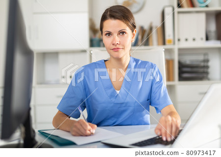 Positive female doctor working on laptop Positive female doctor working on laptop 80973417