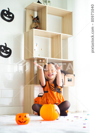 Portrait little girl in the witch dress throws lot of chocolate in the air in the room decorated in Halloween festival Portrait little girl in the witch dress throws lot of chocolate in the air in the room decorated in Halloween festival 80973840