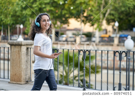 woman listens to music with her headphones connected to her smartphone 80974051