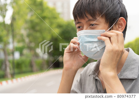Portrait of ill young Asian man, person wearing a face mask for corona virus and health care concept in quarantine. Wearing medical mask. 80974377