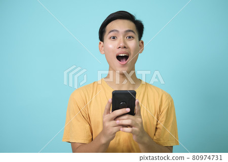 Portrait of a shocked young man using mobile phone. 80974731