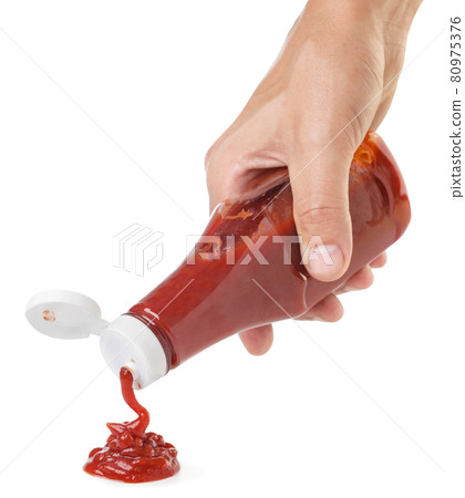 Ketchup squeezes out of a bottle hand on a white background. Isolated Ketchup squeezes out of a bottle hand on a white background. Isolated 80975376