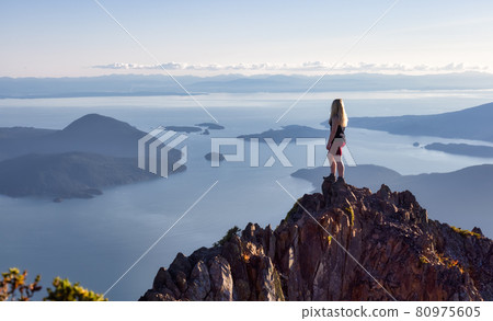 Adventurous Caucasian Woman Hiking on top of a Rocky Mountain Cliff 80975605