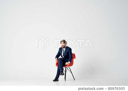 man in suit sitting on red chairs emotions office light background 80976305