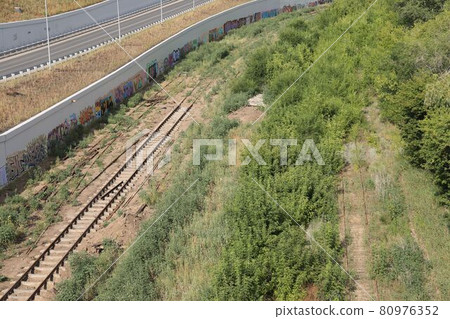 Abandoned railway tracks are overgrown with grass, the rails lie along the road, Samara, July 2021 Abandoned railway tracks are overgrown with grass, the rails lie along the road, Samara, July 2021 80976352