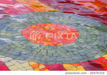 The bottom of the fountain is lined with multi-colored tiles, the surface above the mosaic bottom, the background The bottom of the fountain is lined with multi-colored tiles, the surface above the mosaic bottom, the background 80976358