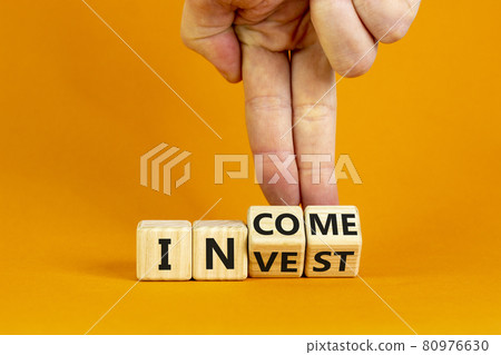 Invest or income symbol. Businessman turns wooden cubes and changes the word 'invest' to 'income'. Beautiful orange background, copy space. Business and invest or income concept. 80976630