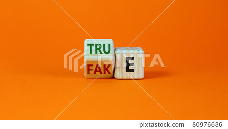Fake or true symbol. Turned a wooden cube and changed the word 'fake' to 'true' or vice versa. Beautiful orange table, orange background, copy space. Business and fake or true concept. 80976686