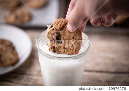 dipping chocolate chip cookie into milk dipping chocolate chip cookie into milk 80976976