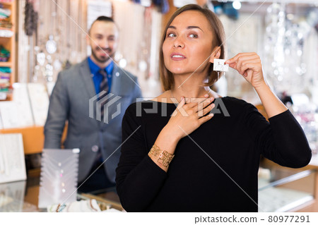 Portrait of female consumer trying earrings 80977291