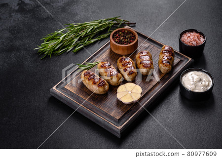 Grilled sausage with the addition of herbs and vegetables on the dark background Grilled sausage with the addition of herbs and vegetables on the dark background 80977609