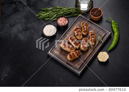 Grilled sausage with the addition of herbs and vegetables on the dark background Grilled sausage with the addition of herbs and vegetables on the dark background 80977610