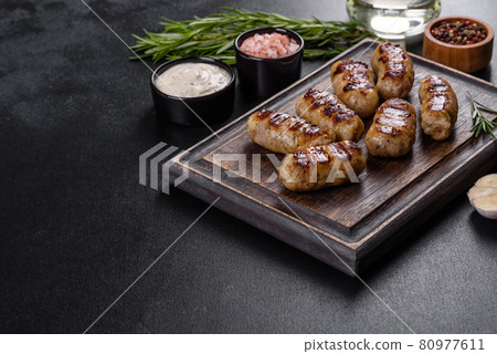 Grilled sausage with the addition of herbs and vegetables on the dark background Grilled sausage with the addition of herbs and vegetables on the dark background 80977611