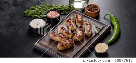 Grilled sausage with the addition of herbs and vegetables on the dark background Grilled sausage with the addition of herbs and vegetables on the dark background 80977612