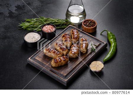 Grilled sausage with the addition of herbs and vegetables on the dark background Grilled sausage with the addition of herbs and vegetables on the dark background 80977614