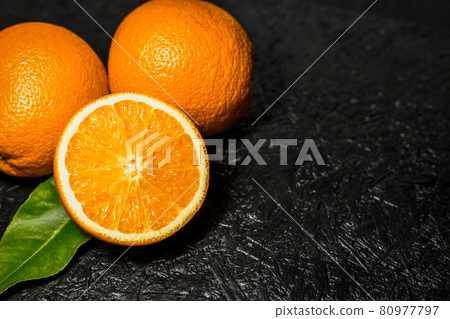 Sliced and whole oranges on dark background Sliced and whole oranges on dark background 80977797