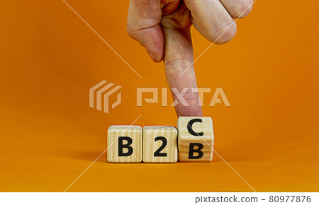 Business to Business or Busness to Consumer. Businessman turns a cube and changes words 'B2C' to 'B2B' or vice versa. Business, B2B or B2C concept. Beautiful orange background, copy space. 80977876