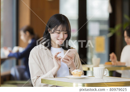 A young woman operating a smartphone in a cafe A young woman operating a smartphone in a cafe 80979025