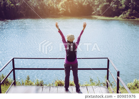 Happy backpacking woman standing with hands raise up and looking beautiful view at outdoor Happy backpacking woman standing with hands raise up and looking beautiful view at outdoor 80985976