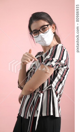 Young woman showing COVID-19 vaccine bandage merrily Young woman showing COVID-19 vaccine bandage merrily 80986935