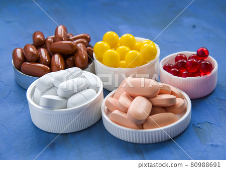 A group of vitamins on a blue background. 5 types of dietary supplements of different colors 80988691